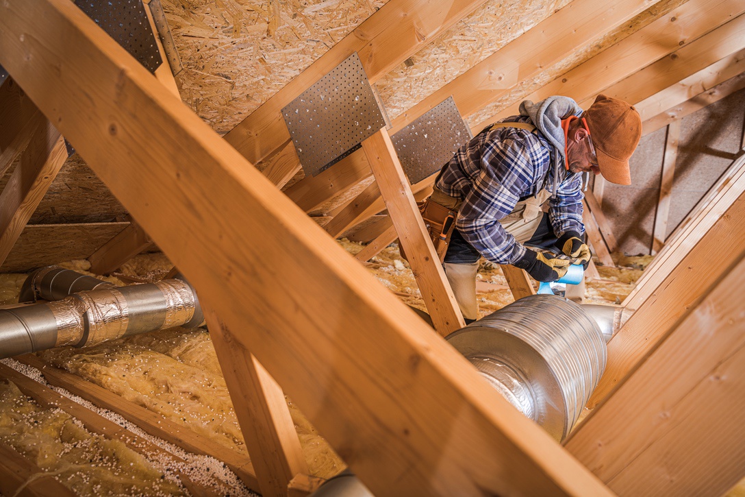 Professional HVAC technician installing multi-zone heating equipment in ductwork of home
