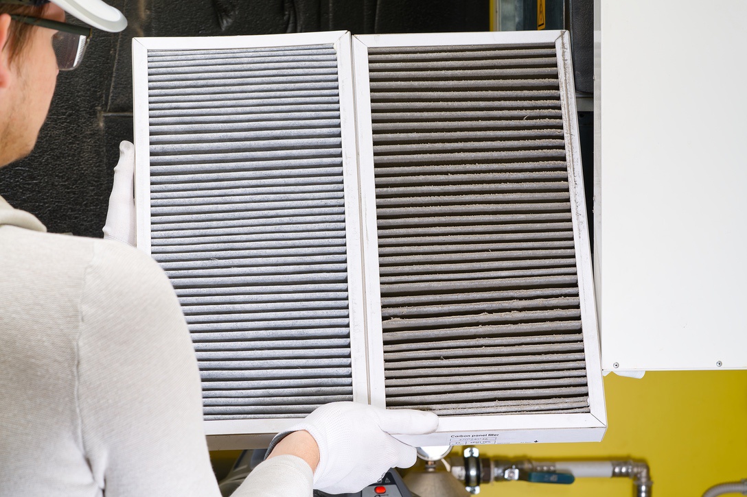 Furnace technician replacing dirty furnace filter in home