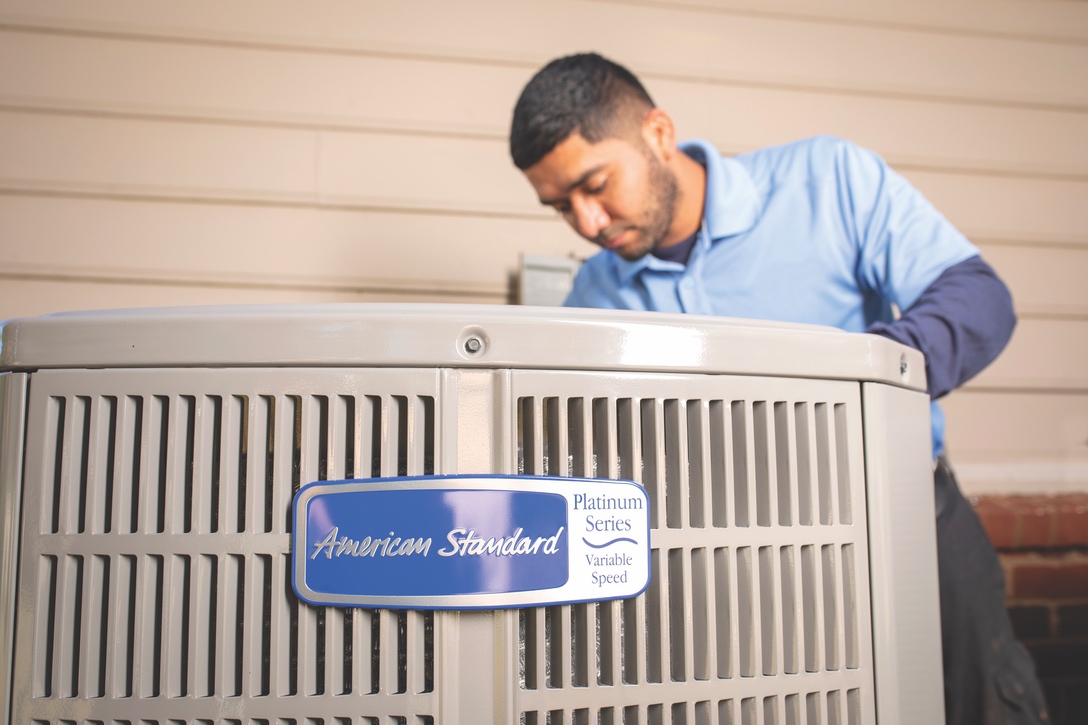 AC tech performing professional maintenance on air conditioner outdoor unit